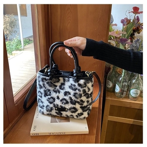 Détail d'un sac à main en peluche imprimé léopard avec des poignées en cuir noir