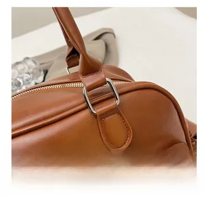 Detail of brown leather handbag featuring silver square metal buckle and fine stitching