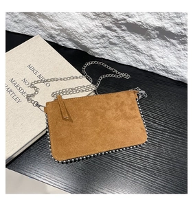 Detail view of brown suede shoulder bag with silver bead trim and metal chain strap