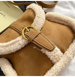 Détail du sac en daim marron avec bordure en sherpa et boucle dorée élégante