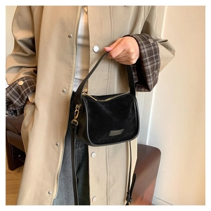 Detail of black suede and smooth leather shoulder bag with golden hardware
