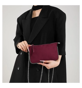 Close-up of matte burgundy crossbody bag with silver rivet trim and metal chain