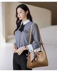 Detailed view of a brown pebbled leather handbag with a patterned silk scarf on the handle
