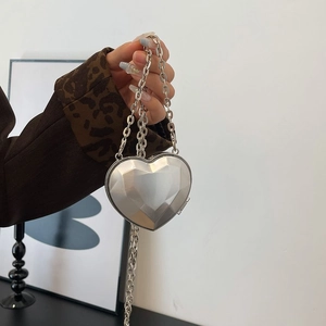 Close-up of heart-shaped silver geometric evening bag with multi-faceted metallic finish
