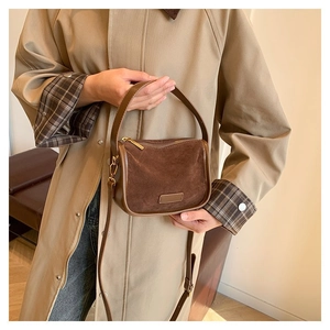 Brown half-moon PU leather crossbody bag worn by model in a minimalist studio setting