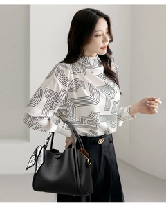 Detail of elegant high-neck printed blouse with puff sleeves and metal cuff buttons