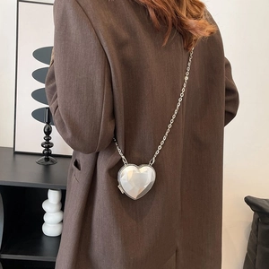 Detailed close-up of a silver geometric heart-shaped crossbody bag with a sleek metal chain
