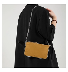 Detail of ginger yellow shoulder bag with silver beaded trim and metal chain strap