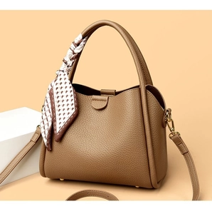 Detail view of khaki pebbled leather handbag with adjustable strap and geometric silk scarf