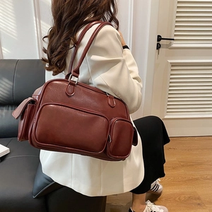 Detail view of retro reddish-brown leather shoulder bag with multiple zipper pockets