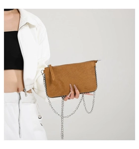 Close-up of brown frosted leather crossbody bag with decorative silver chain detail