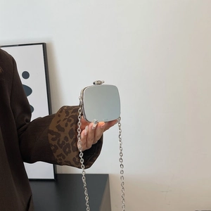 Detail of high-polish silver mini acrylic bag featuring a metal chain and push-lock closure