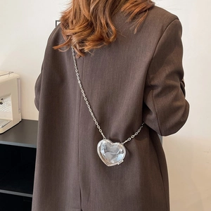 Detail of heart-shaped acrylic mini bag with geometric cut texture and silver chain strap