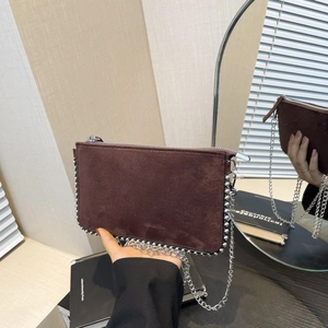 Detail of brown matte suede crossbody bag featuring silver chain and metal ball trim