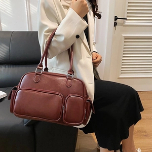Detail of wine red PU leather tote bag with multiple zipper pockets on model
