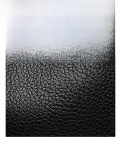 Macro detail of glossy black oil wax leather texture with clear grain and shiny finish