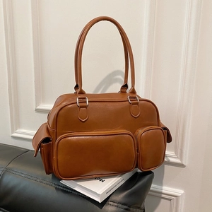 Detail of brown PU leather crossbody bag with multiple front pockets on a black bench