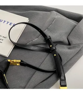 Detail of adjustable black leather shoulder strap with polished gold buckle and hardware