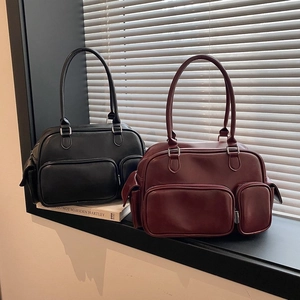 Detail of classic black and burgundy tote bags featuring front zipper pockets and leather texture