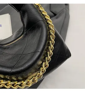 Detail of black wrinkled leather hobo bag with chunky gold chain strap and metal zipper