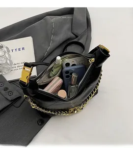 Detailed interior view of black crossbody bag with gold chain and everyday essentials