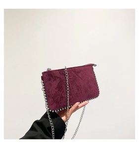 Detail of burgundy suede shoulder bag featuring silver studded edges and elegant chain strap