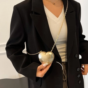 Detail of a heart-shaped gold acrylic mini bag with a geometric surface and chain