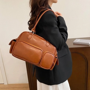 Detailed side view of a brown vintage leather tote bag with multiple zipper pockets