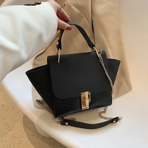 Elegant black winged handbag with gold lock and crocodile texture on a minimal background