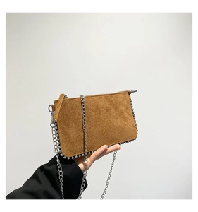 Detail of a brown suede shoulder bag with silver bead trim and a thin metal chain strap