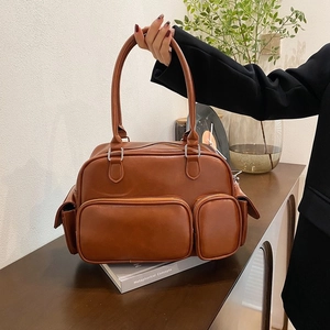 Detailed view of caramel PU leather handbag with dual front zippers and D-ring handle