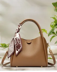 Detail of brown litchi pattern leather handbag featuring a silk scarf and gold studs