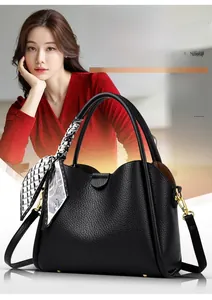 Detail of black pebbled leather handbag with wavy edge and geometric silk scarf