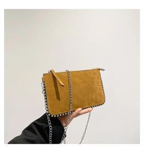 Detail of ochre suede envelope bag with silver beaded edges and thin metal chain strap