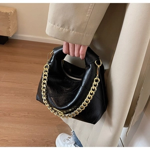 Detail of black pleated faux leather dumpling bag with chunky gold chain strap