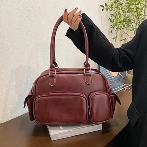 Detail view of burgundy PU leather handbag showing multiple pockets and stitching accents