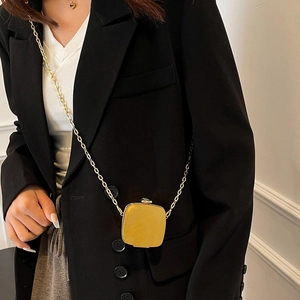 Detail of yellow minimalist mini bag with golden metal buckle and sleek chain strap