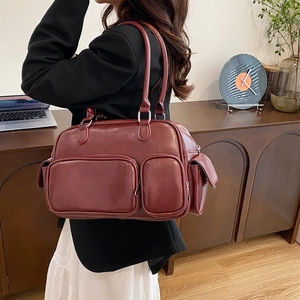 Detail of burgundy leather shoulder bag with double zip pockets in a home office setting