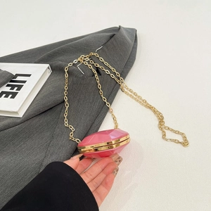 Macro detail of pink acrylic geometric pattern on a mini bag with golden chain