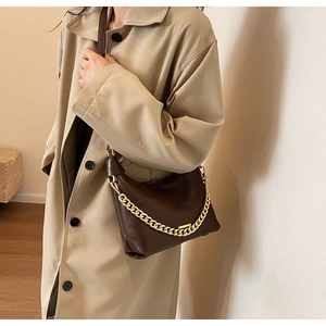 Detail of dark brown quilted leather dumpling bag with chunky gold chain strap decoration