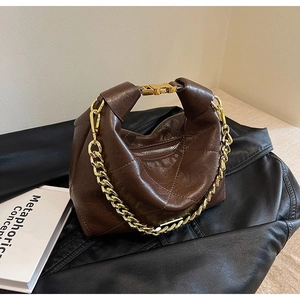 Detail of dark brown quilted leather handbag with gold chain strap and metal buckle