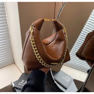 Detail of a brown quilted leather hobo bag with a thick gold chain and metallic buckle