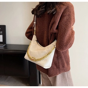 Detail view of cream quilted dumpling bag with gold chain and leather strap on model