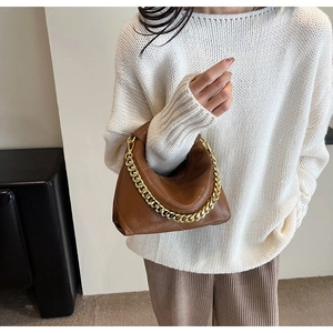 Close-up of quilted brown crescent bag with chunky gold chain strap and stylish leather texture