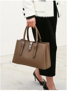 Brown faux leather tote bag with pebble texture and silver buckle shown on a model