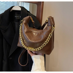 Detail of dark brown quilted crescent bag featuring gold chain and smooth zipper closure
