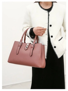 Detail of dusty pink PU leather tote bag with metallic buckle worn by a model in white blazer