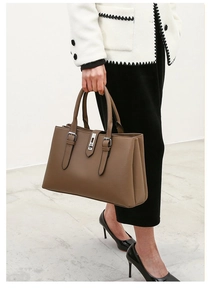 Detail of premium brown pebble leather tote bag featuring stitching and silver turn-lock