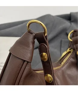 Détail d'un sac en cuir marron foncé avec anneau en D doré et rivets métalliques