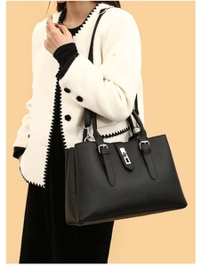 Detail of black tote bag with silver twist lock and pebble leather texture